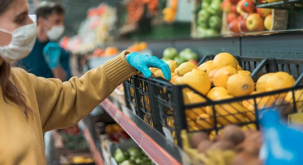 Acheteurs en masques protecteurs choisissant des fruits au supermarché — Photo