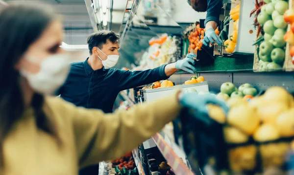 Acheteurs en masques protecteurs choisissant des fruits au supermarché — Photo