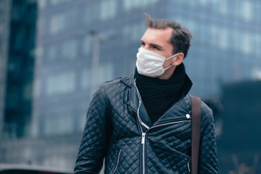 Koruyucu maskeli adam kendinden emin bir şekilde ileriye bakıyor.