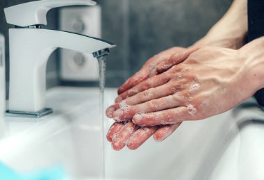 Kapat. Genç adam ellerini dikkatlice sabunluyor. .