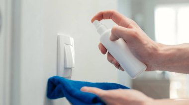 Kapat. Duvardaki düğmeye antibakteriyel sprey sıkan bir adam..