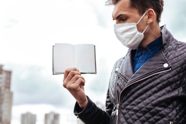 Kapat. Koruyucu maskeli bir adam pasaportunu sunuyor..