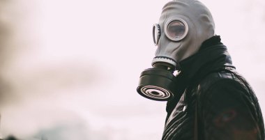 Boş bir şehirde sokakta duran gaz maskeli sıradan bir genç adam.