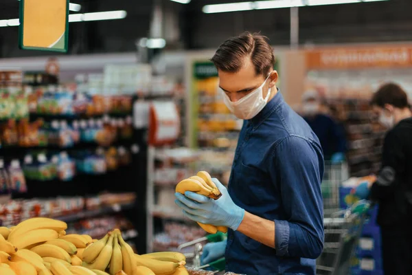 Client en gants de protection choisissant des bananes dans un supermarché — Photo