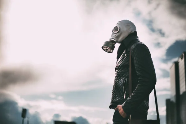 Jovem casual em uma máscara de gás em pé na rua em uma cidade vazia — Fotografia de Stock