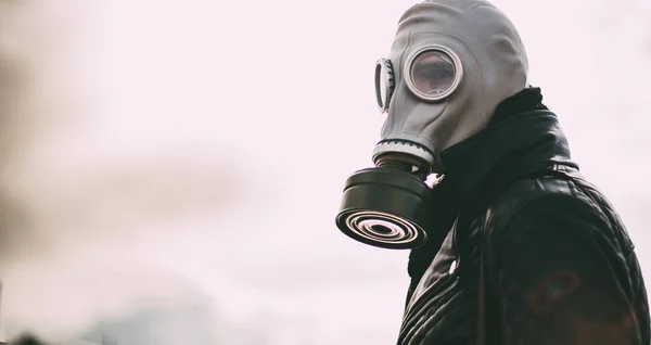 casual young man in a gas mask standing on the street in an empty city