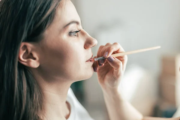 Maquillaje artista aplica brillo labial en un salón de belleza. —  Fotos de Stock