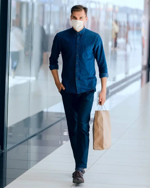 Homme dans un masque de protection passant près d'un supermarché. — Photo