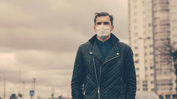 Man met een beschermend masker kijkt naar de lege straat — Stockfoto