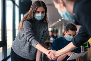 Koruyucu maskeli genç personel el sıkışıyor..