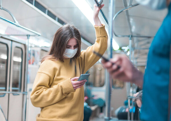 people with smartphones standing in a subway car.