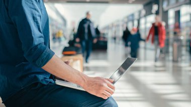 Koruyucu maskeli bir adam şehir binasının yakınındaki bir laptopta çalışıyor..