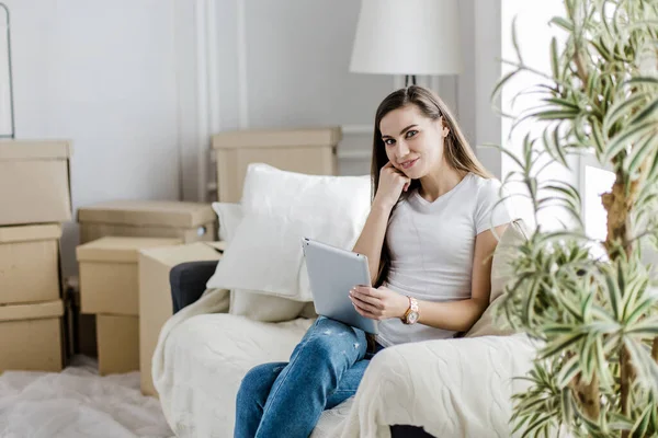 Mladá žena s digitálním tabletem sedí na pohodlné pohovce — Stock fotografie