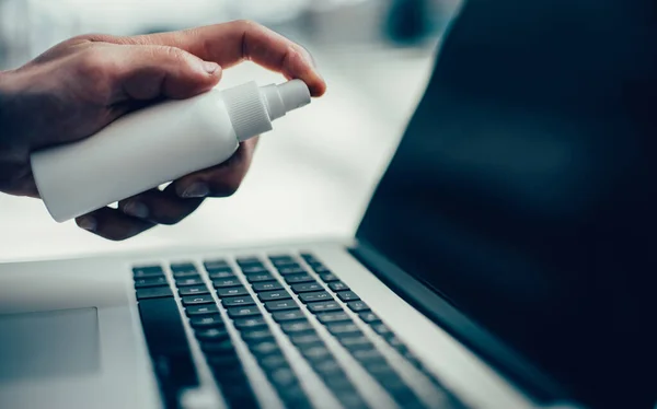 Jonge man ontsmetten zijn laptop met antiseptische — Stockfoto