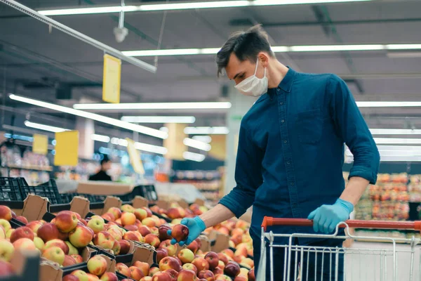 Young man in a protective mask standing near the counter with apples — Stock Photo, Image