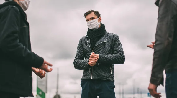 Jovens em máscaras protetoras falam em pé a uma distância segura — Fotografia de Stock