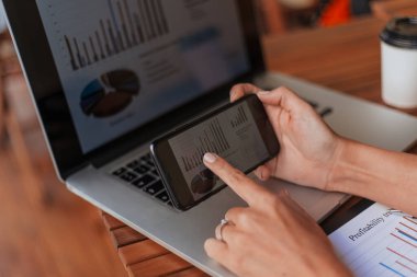 İş kadını finansal verileri analiz etmek için akıllı telefonu kullanıyor.