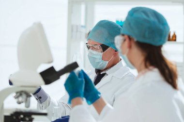 Kapat. Kadın bilim adamı mikroskoptan bakıyor. .