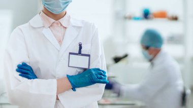 Laboratuvarda duran boş rozetli kadın bilim adamı..