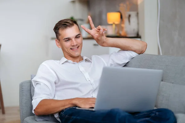 Atraktivní muž mluví přes video odkaz ve svém obývacím pokoji . — Stock fotografie