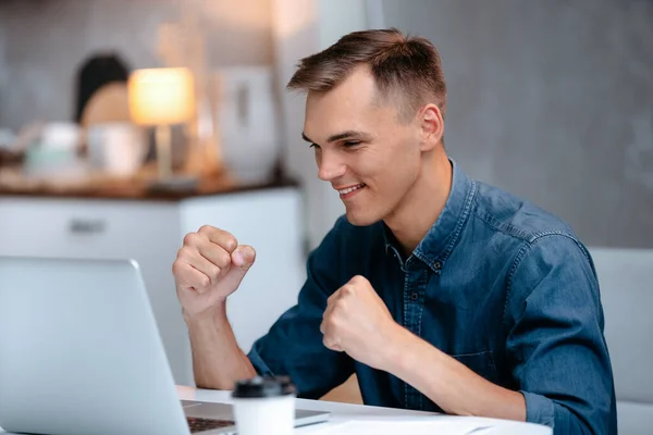 Glücklicher junger Mann liest die Nachrichten auf seinem Laptop. — Stockfoto