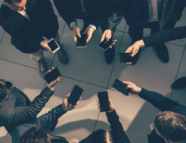 close up. young business people with smartphones standing in a circle.