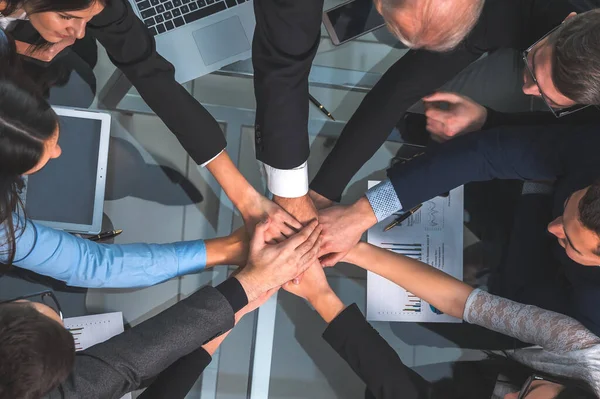 Vista superior. empleados felices uniendo sus manos sobre el escritorio. — Foto de Stock