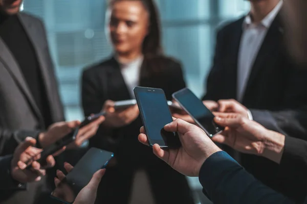 Grupo de jovens empresários com smartphones em pé em um círculo — Fotografia de Stock