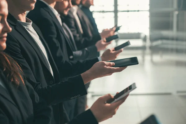 Jovens empresários com smartphones em pé na fila — Fotografia de Stock