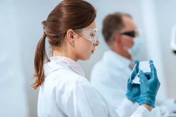 Científica que se pone una máscara protectora en el laboratorio. —  Fotos de Stock