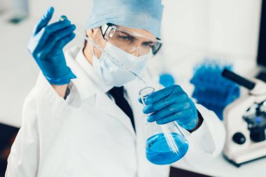 Kapat. Bilim adamı tıbbi şişedeki sıvıyı inceliyor..