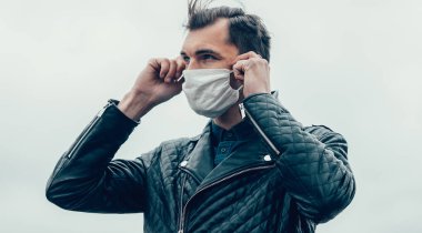 Sokakta duran koruyucu bir maske takan genç adam.