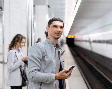 Genç adam metro istasyonunda tren bekliyor..
