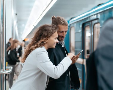 Metroda akıllı telefonları olan genç bir çift. .