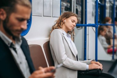 Yorgun genç bir kadın metroda uyuyor..