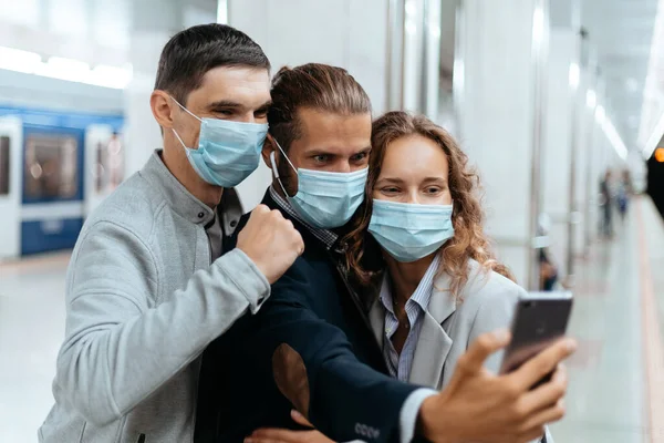 Gruppe von Fahrgästen in Schutzmasken macht Selfies in der U-Bahn. — Stockfoto