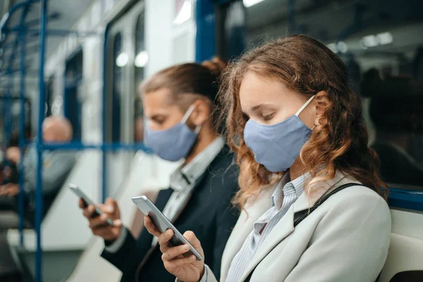 Homem e uma mulher com smartphones sentados em um carro de metrô. — Fotografia de Stock