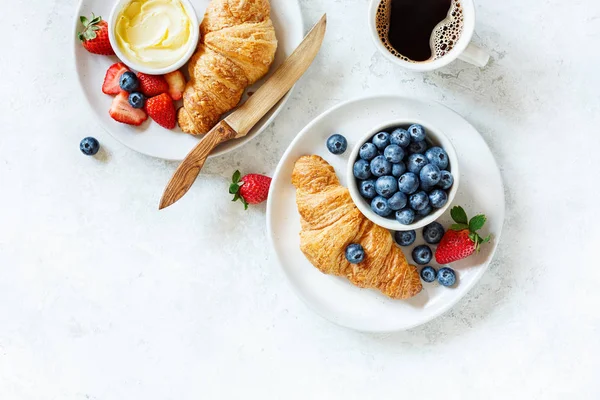 Breakfast with coffee, berries and croissant.