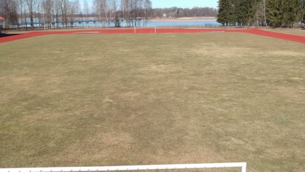 サッカーのゲートと春のフィールド上空を飛んでいる小さな州スタジアム ドローンで — ストック動画