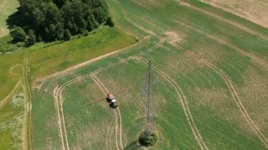 Yüksek elektrik tower, havadan görünümü yakınındaki kimyasallarla kolza tohumu alana püskürtme tarım traktör