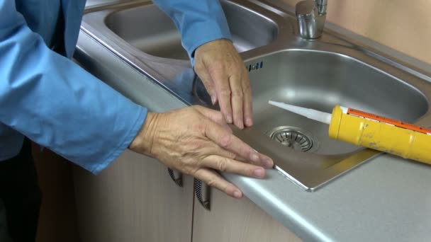 Arbeiterhände fixieren Dichtsilikon-Niveau auf Waschbecken in der Küche