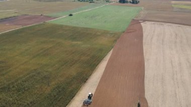 Yazın sonunda hasat edilen tarlaları işleyen traktör, hava manzarası.