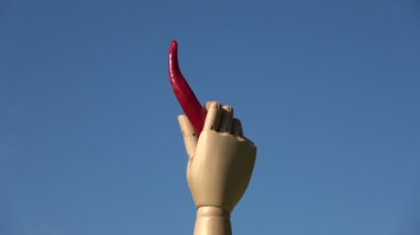 Dönen sanat modeli ahşap el, mavi arka planda kırmızı kırmızı kırmızı kırmızı kırmızı biber tutuyor.
