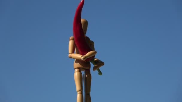 木製のアーティストマネキンを空の背景に回転させ 赤唐辛子を保持する — ストック動画