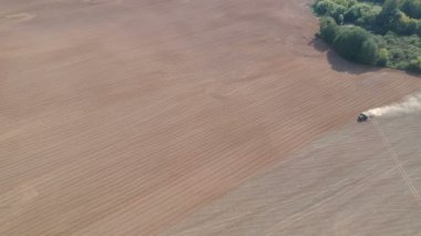 Tarım traktörü tozlu tarlalara ekin ekiyor, havadan bakıyor.