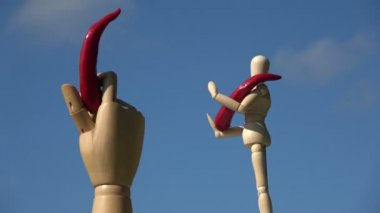 Gökyüzünde dönen ahşap arka plan sanatçısı manikin ve kırmızı acı biberli el.