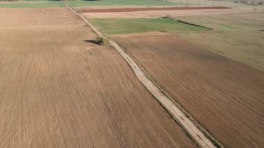 Topraklanmış ve ekilmiş sonbahar tarım arazileri ve boş kötü çakıl yolu, hava manzarası