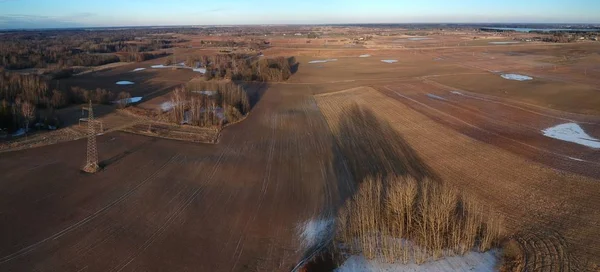 Early spring farmland fields with puddle and evening shadow, aerial