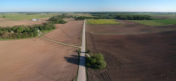 Cultivated farmland fields and white gravel road in spring, aerial