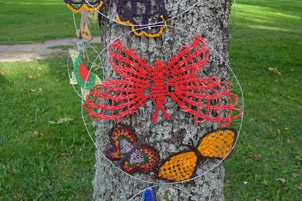 Colorful knitted butterflies on tree in summer park — Stock Photo, Image